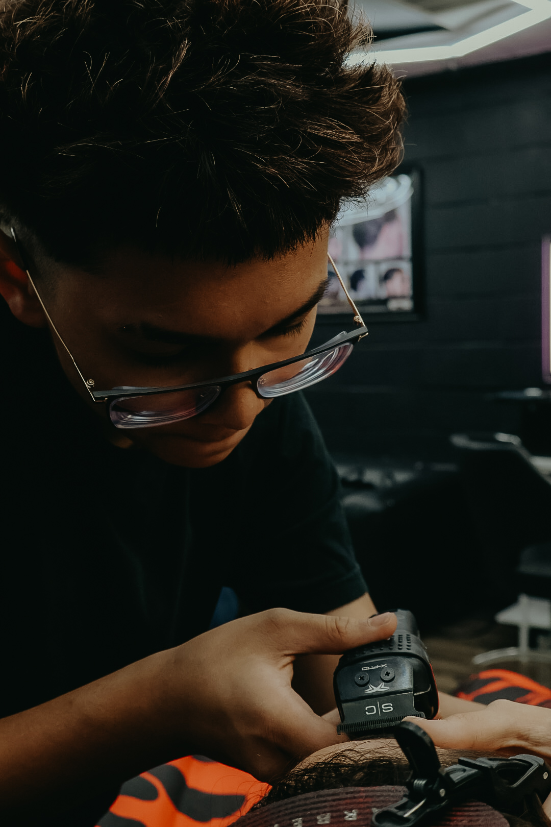 Cameron Chhuth leaning in close while lining up a client's cut.
