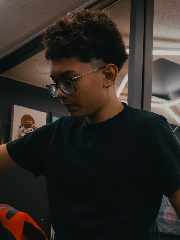 Portrait of Cameron Chhuth working in the barbershop.