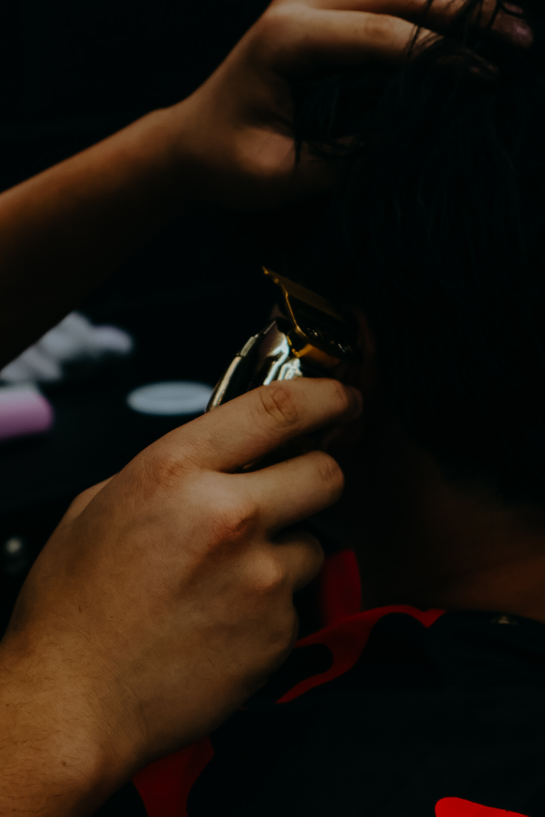Close-up of Cameron's hands using clippers along a client's hairline.